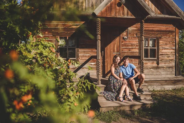 Un par de hombres y mujeres en el pueblo, cerca de una casa de madera. Estilo country. Verano rústico . — Foto de Stock