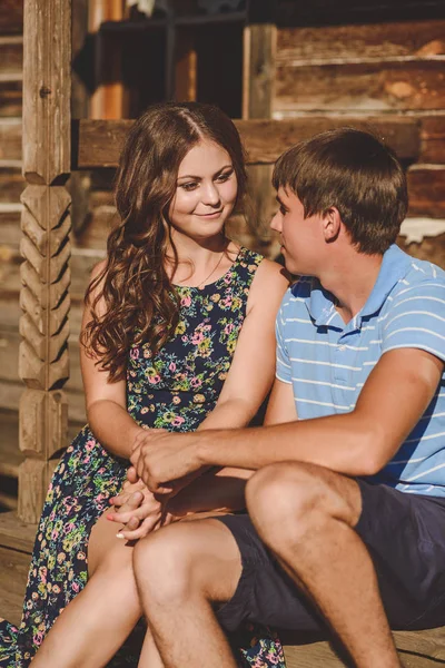 Un par de hombres y mujeres en el pueblo, cerca de una casa de madera. Rostros cerca el uno del otro. Concepto: amor, romance, verano . — Foto de Stock