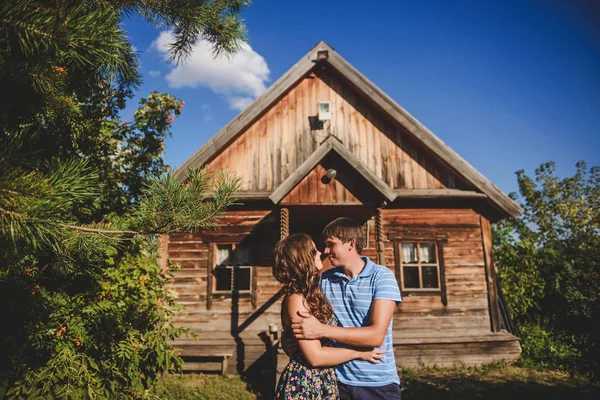 Liefdevolle romantische koppel in het dorp, in de buurt van een houten huis. Man omvat een jonge vrouw. Concept: liefde, romantiek, zomer. — Stockfoto