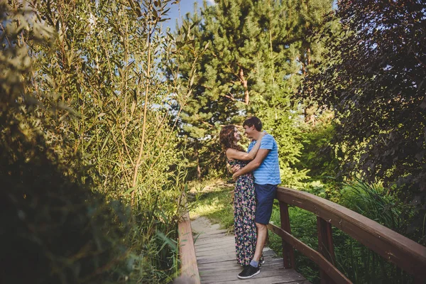 Gelukkig romantisch koppel in het dorp, wandelen op de houten brug. jong mooi vrouw en man knuffelen elkaar. — Stockfoto