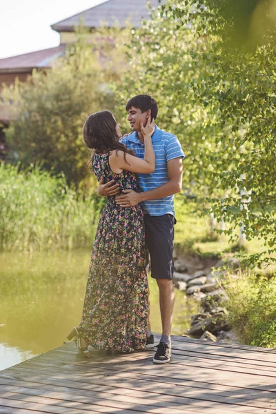 Gelukkig romantisch koppel in het dorp, wandelen op de houten brug in de buurt van het meer. jong mooi vrouw en man knuffelen elkaar. — Stockfoto