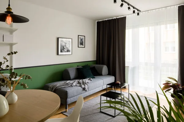 Kleines Wohnzimmer Mit Rundem Hölzernem Esstisch Und Schlichtem Grauen Sofa — Stockfoto