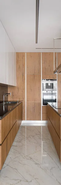 Vertical panorama of stylish kitchen with wooden furniture, kitchen island and marble floor tiles