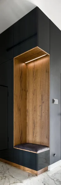 Vertical panorama of elegant home corridor with black wall, wooden seat and marble floor