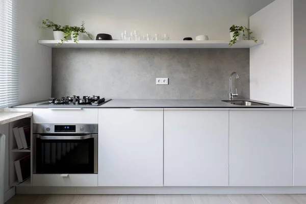 白の食器棚とバックスプラッシュ付きグレーのカウンター付きのシンプルでスタイリッシュなキッチンインテリア — ストック写真