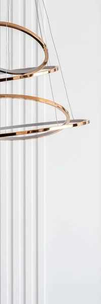 Vertical panorama of stylish gold chandelier and decorative white molding on the wall in the background