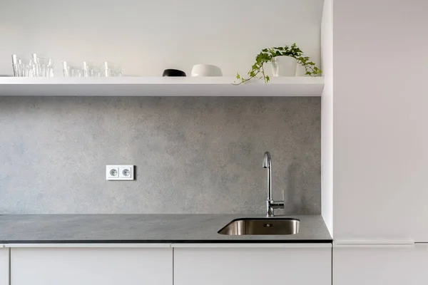 Simple sink in modern kitchen with gray countertop and white furniture