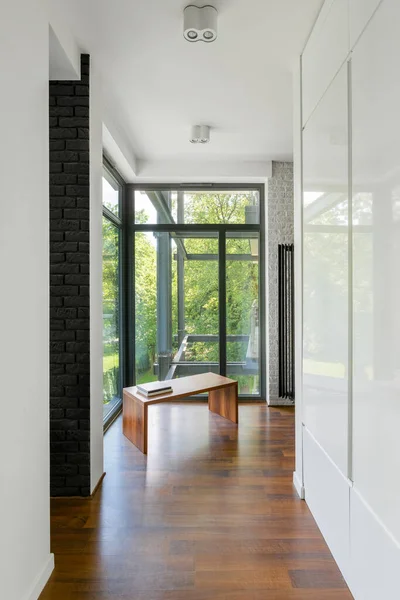 Home corridor with window wall, wooden floor and white gloss wardrobe