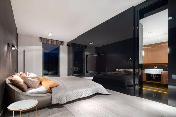 Luxury bedroom with black gloss wall and open doors to elegant bathroom
