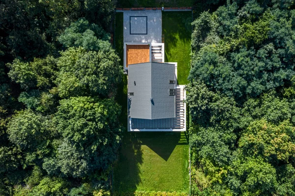Big and stylish family house with garden in green forest, aerial drone view