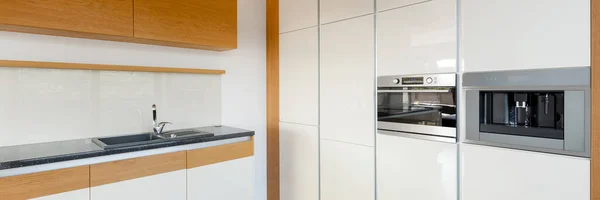 现代白色光泽厨房全景 配有时尚的木制橱柜和木制墙面装饰 — 图库照片
