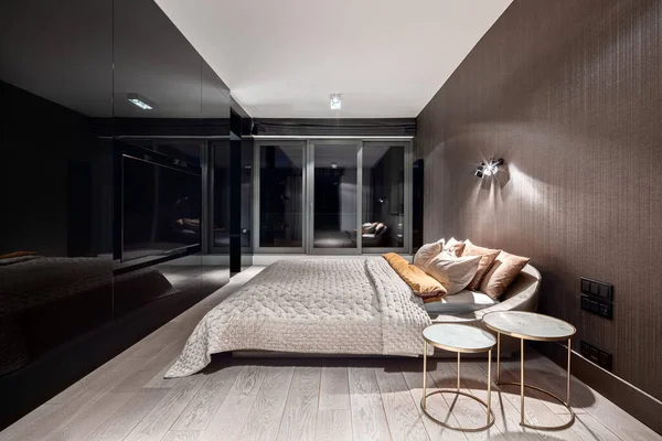 Elegant bedroom with vinyl wallpaper and mirrored black wall with tv at night