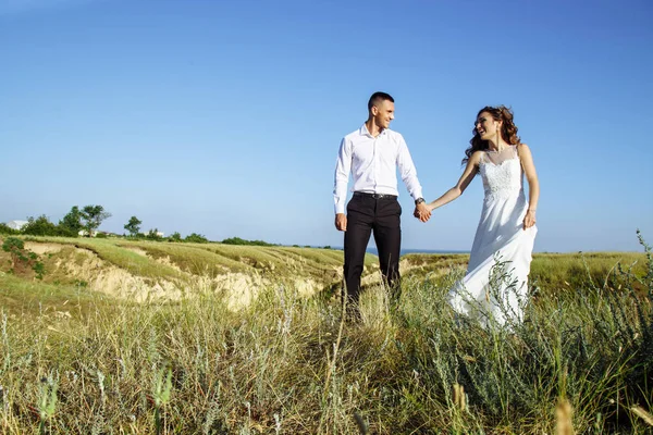 Belo casal no campo, Amantes ou recém-casados posando no pôr do sol com céu perfeito — Fotografia de Stock