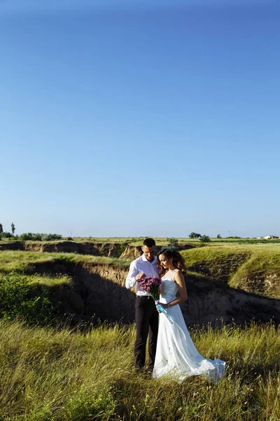 Hermosa pareja en el campo, amantes o recién casados posando en la puesta del sol con el cielo perfecto — Foto de Stock