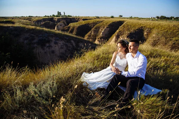 Hermosa pareja en el campo, amantes o recién casados posando en la puesta del sol con el cielo perfecto — Foto de Stock