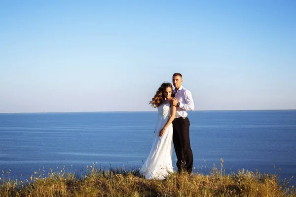 Hermosa pareja en el campo, amantes o recién casados posando en la puesta del sol con el cielo perfecto — Foto de Stock