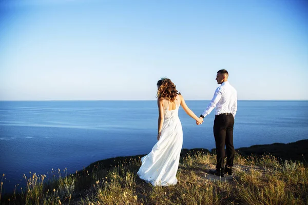 Belo casal no campo, Amantes ou recém-casados posando no pôr do sol com céu perfeito — Fotografia de Stock