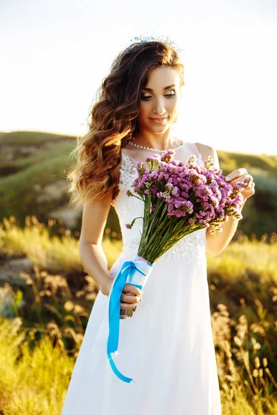 Mujer joven en vestido de novia al aire libre. hermosa novia en un campo al atardecer — Foto de Stock