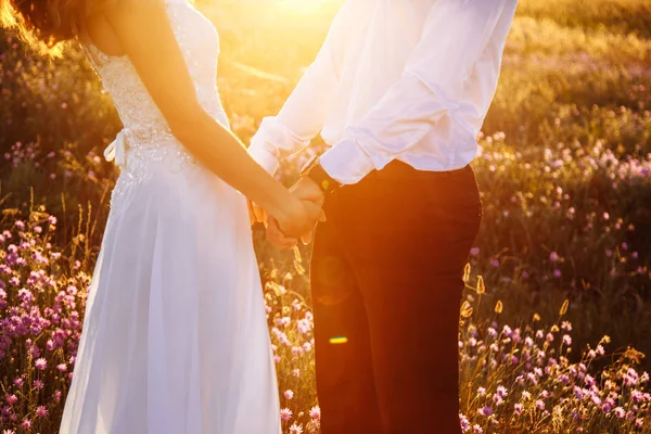 Hermosa pareja en el campo, amantes o recién casados posando en la puesta del sol con el cielo perfecto — Foto de Stock