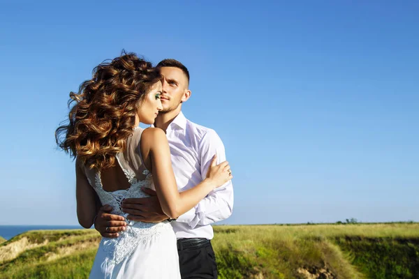 Belo casal no campo, Amantes ou recém-casados posando no pôr do sol com céu perfeito — Fotografia de Stock