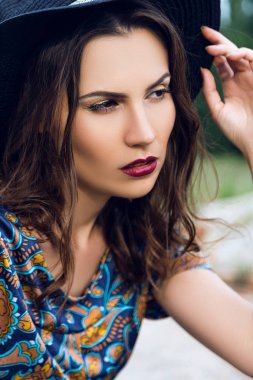 moda açık güzel bir esmer kadın portresi alanında bir takım elbise ve siyah bir şapka giymiş