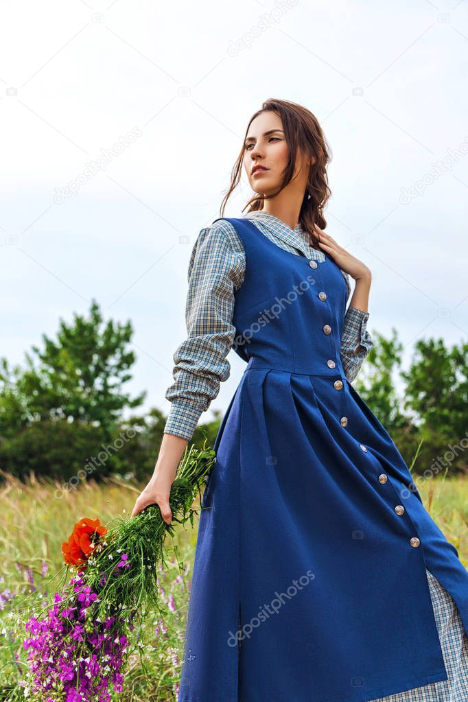 outdoor portrait of a beautiful brunette woman in blue dress in the field