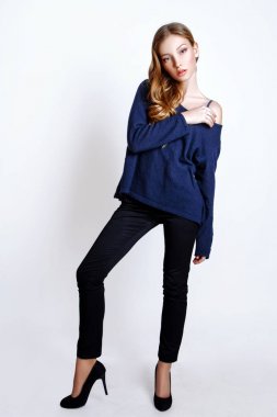 Moda portre sarışın saçlı güzel genç kadın. Kız mavi kazak ve beyaz bir arka plan üzerinde kot pantolon