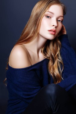 Moda portre sarışın saçlı güzel genç kadın. Kız bir siyah bir zemin üzerine mavi kazak
