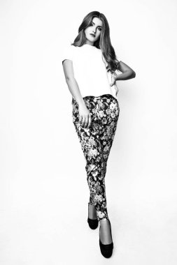 Güzel genç kadın uzun saçlı moda portre. Kız beyaz bir bluz ve pantolon beyaz bir arka plan üzerine. Siyah ve beyaz