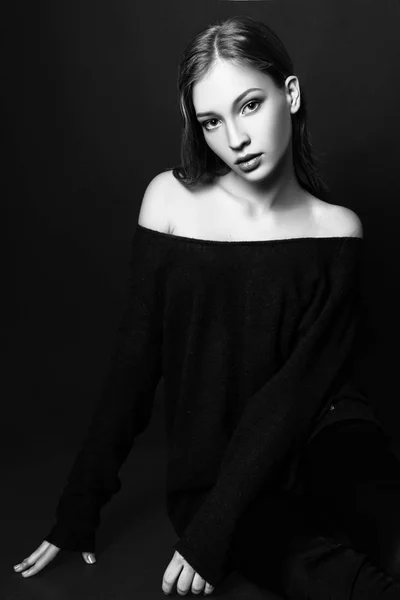 Retrato de moda de una hermosa joven con el pelo rubio. Chica en un jersey azul sobre un fondo negro. Blanco y negro —  Fotos de Stock