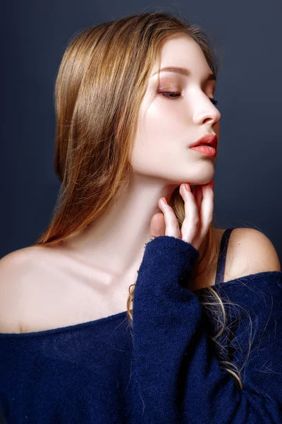 Portret van de mode van mooie jonge vrouw met blond haar. Meisje in een een blauwe trui op een zwarte achtergrond — Stockfoto