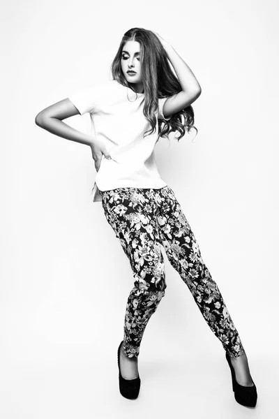 Retrato de moda de bela jovem com cabelo comprido. Menina em uma blusa branca e calças em um fundo branco. Preto e branco — Fotografia de Stock