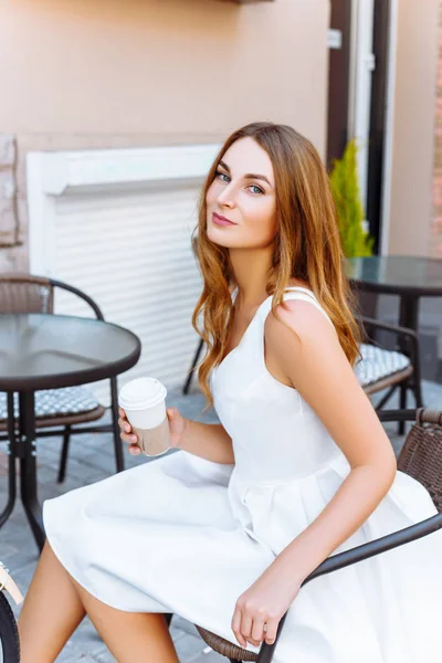 La chica está sentada en la calle con café y una bicicleta — Foto de Stock