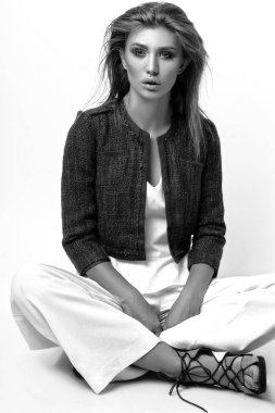 Genç kadın beyaz giysiler ve Studio beyaz bir arka plan üzerinde poz mavi ceket giymiş. Siyah ve beyaz phot