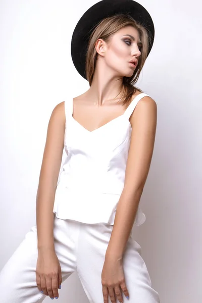 在白色的西装，黑色的帽子，在白色背景上的工作室的女孩. — 图库照片