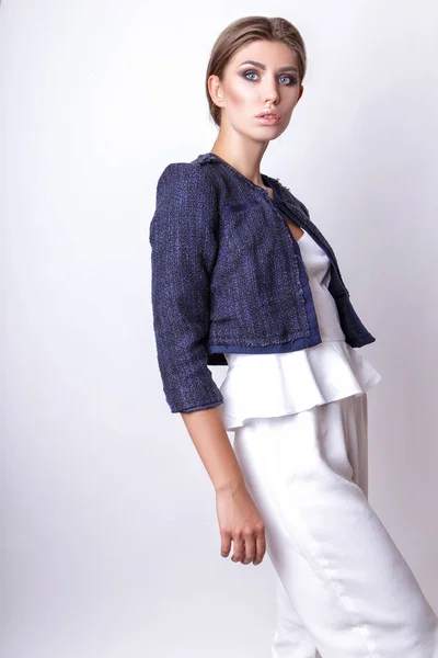 Chica elegante en un traje blanco y chaqueta azul en el estudio sobre un fondo blanco — Foto de Stock