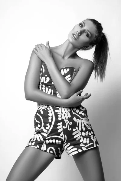 Young woman in green overalls posing in studio on white background. Black and white phot — Stock Photo, Image