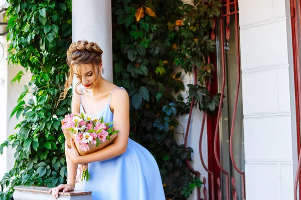 Beyaz column yakınındaki bir buket konumu olan mavi elbiseli kız