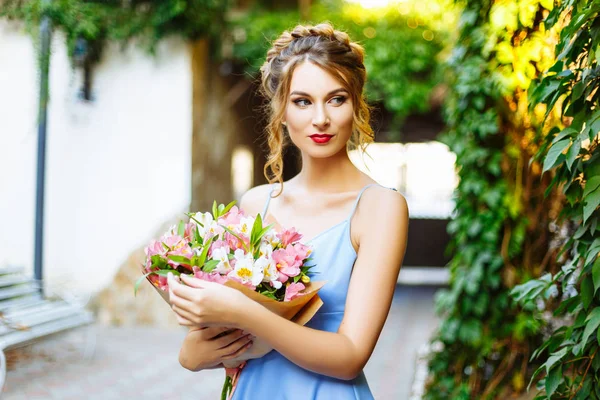 Ung kvinna i blå klänning med blombukett — Stockfoto