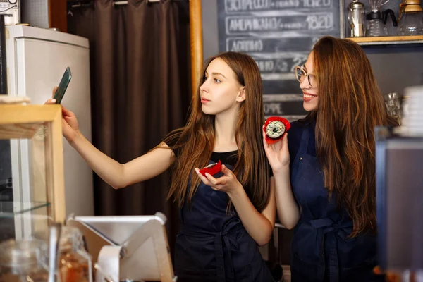 Donuts onların elinde tutan ve selfies yaparak iki mutlu kızlar baristas — Stok fotoğraf