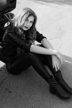 bir motosiklet yakınındaki deri giysili genç kadın. Siyah ve beyaz fotoğraf