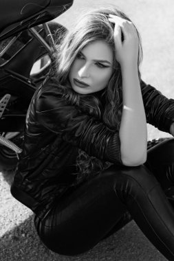 bir motosiklet yakınındaki deri giysili genç kadın. Siyah ve beyaz fotoğraf