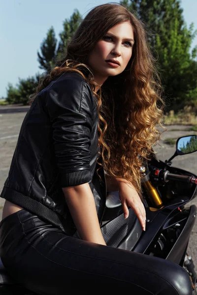 bir motosiklet yakınındaki deri giysili genç kadın