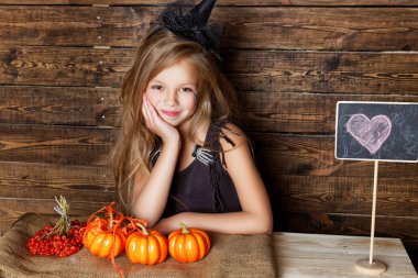 küçük kız bir cadı gibi giyinmiş kabaklar satıyor