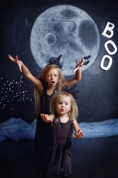 Niña vestida como una bruja asusta y la captura de su hermana — Foto de Stock