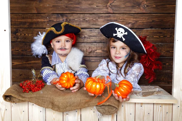 Chico y chica divertidos en trajes de pirata en el estudio con paisajes para Halloween — Foto de Stock