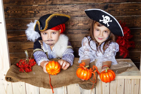 Chico y chica divertidos en trajes de pirata en el estudio con paisajes para Halloween — Foto de Stock