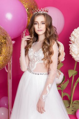 Genç kız elbise ve taç pembe bir arka plan üzerinde