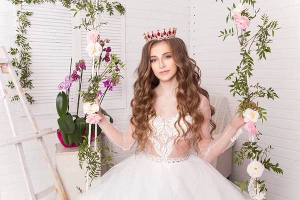Chica joven en la corona y vestido blanco en el estudio sobre un fondo claro — Foto de Stock