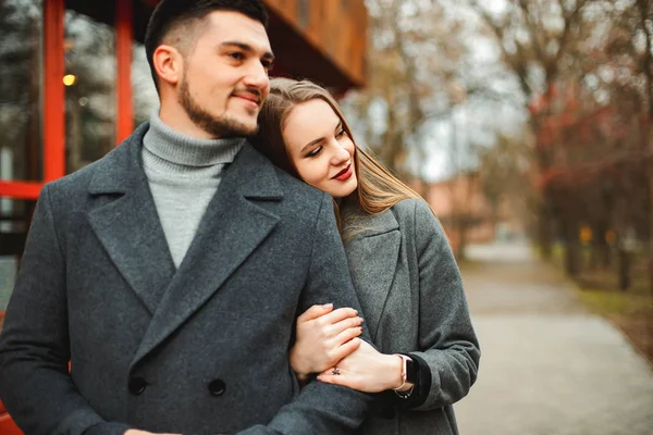 Любящая пара в пальто ходить по улице — стоковое фото